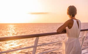 Cruise ship luxury travel holiday destination woman on Europe summer vacation. Elegant lady relaxing on outdoor deck looking at view of Mediterranean Sea.